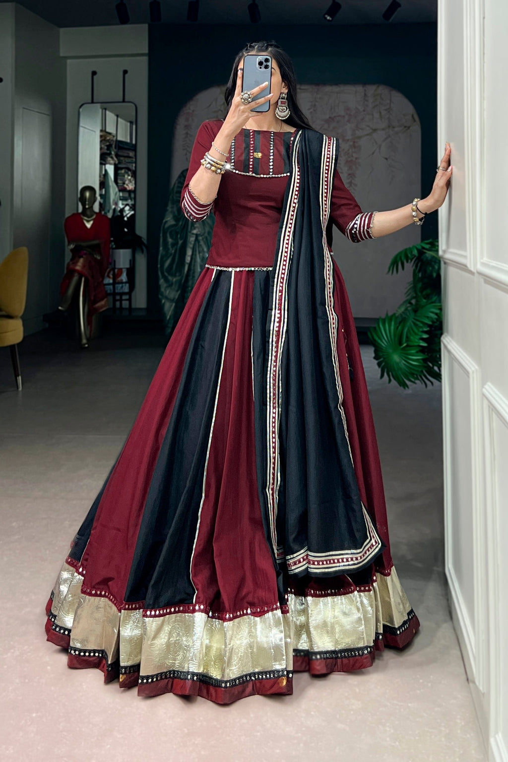 Woman taking a mirror selfie wearing a maroon and black traditional navratri outfit
